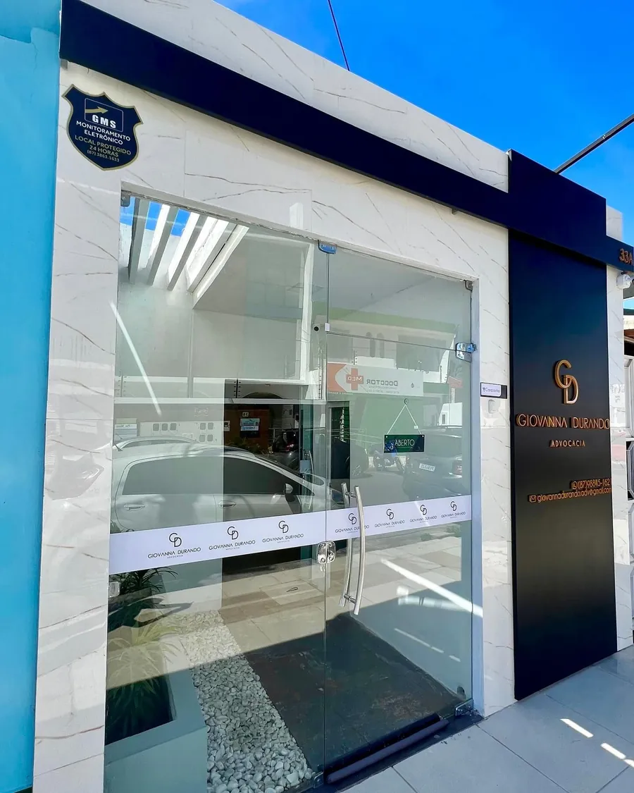 Fachada do escritório na Rua Santa Luzia, com porta de vidro e o painel preto com o monograma dourado